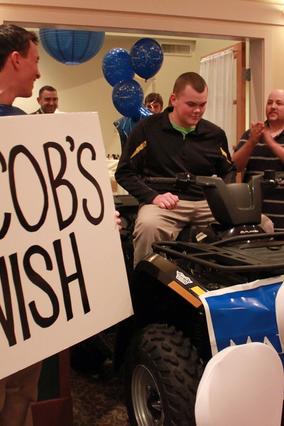 Jacob sits on his ATV surrounded by family and friends