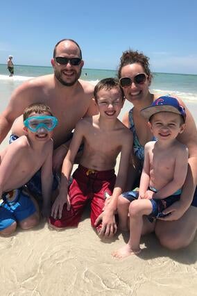 Henry and his family smile in front of the ocean.