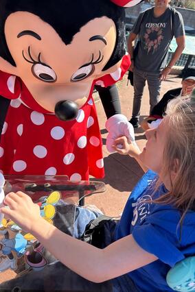Wish kid Poseidon meeting Minnie Mouse as she leans down holding his hands