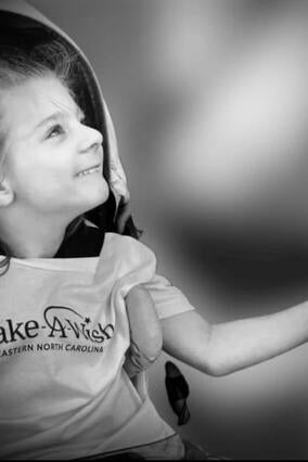 Black and white photo of wish kid Poseidon looking up smiling toward the sun