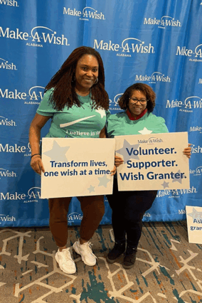 Two volunteers stand side-by-side holding inspirational signs.