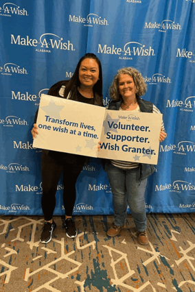 Two volunteers stand side-by-side holding inspirational signs.