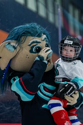 Caleb smiling with Buoy (Kraken Mascot)