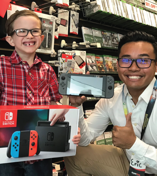 Wish Kid Landon poses with a Gamestop employee with his Nintendo Switch System