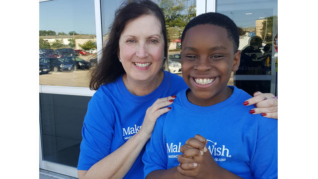 Make-A-Wish volunteer celebrating wish child Kelani's shopping spree wish with him, and both are wearing blue Make-A-Wish t-shirts
