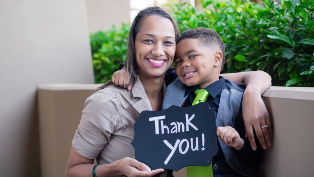 Wish Mom and kid hold a 'thank you' sign