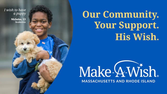 Wish child Nicholas, 13, in a blue jacket holding the goldendoodle puppy that he received for his wish.
