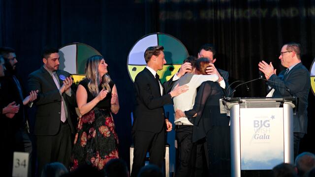 Travis Flores embraced by family on stage