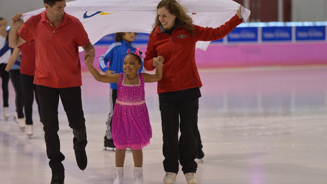 Nicole skating with family holding flag
