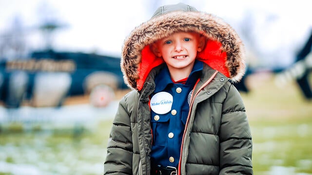 Landen stands outside in front of the helicopter.