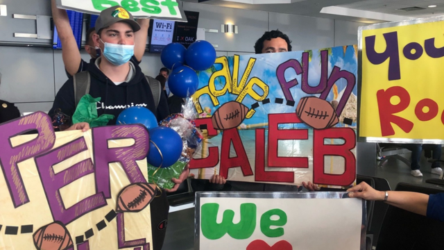 Caleb surrounded by an airport welcome