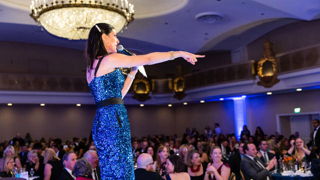 Auctioneer Ellen Toscano points to bidding guests in the audience