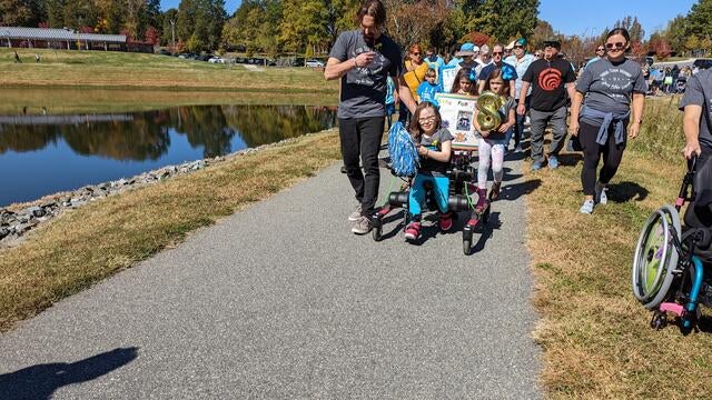 Marcy leading a team of family & friends walking in her Trexo through the park