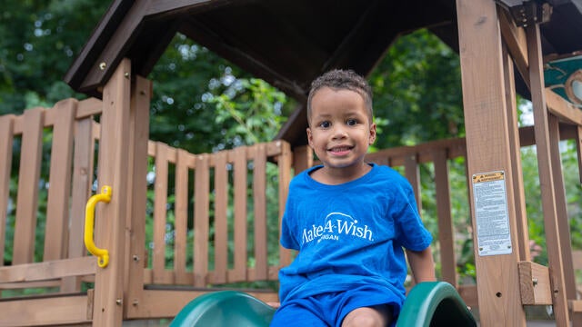 A young boy sitting on his slide about the slide down