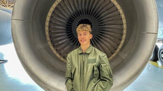Wish Kid Isaiah standing in front of an airplane jet.