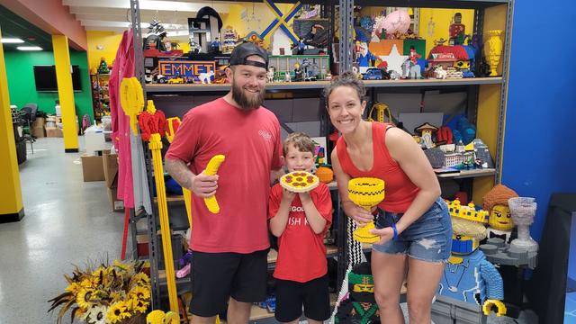 Wish kid Rowan posing with his parents holding lego designs in a store