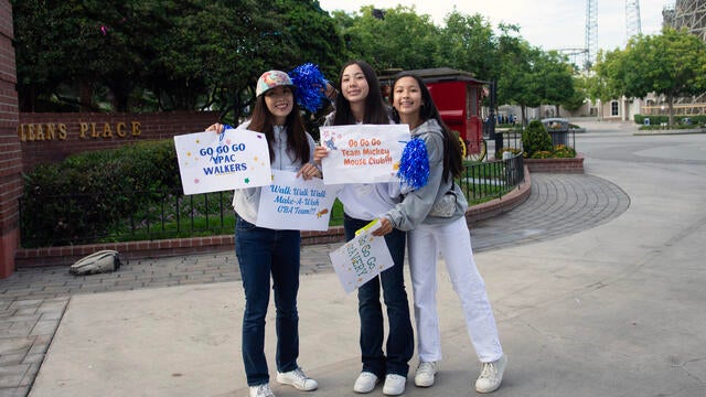 Volunteers hold up signs on the course at Walk for Wishes