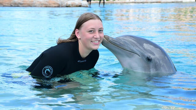 Briana being kissed by a dolphin the water