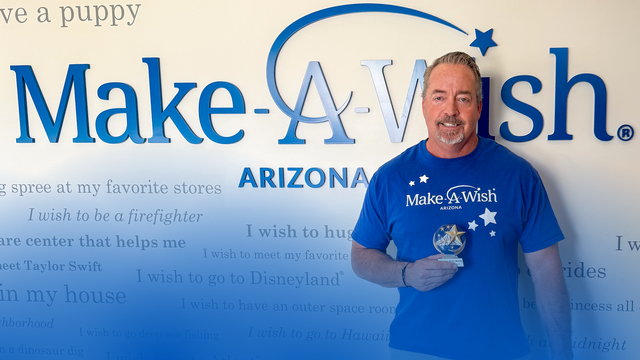 Duke Snider, June volunteer of the month, standing in front of Wish Wall