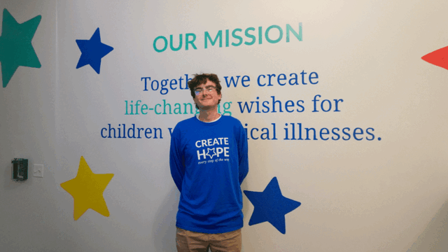 Aidan standing in front of the Make-A-Wish mission statement