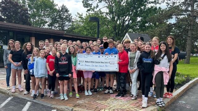 Group of school children holding a check for funds raised for Kids for Wish Kids fundraiser