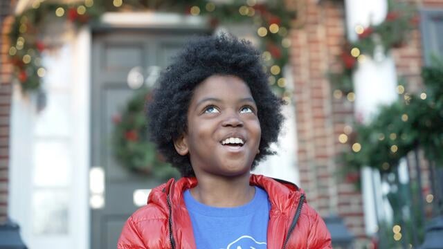 Austin is smiling looking up in front of the Home Alone house