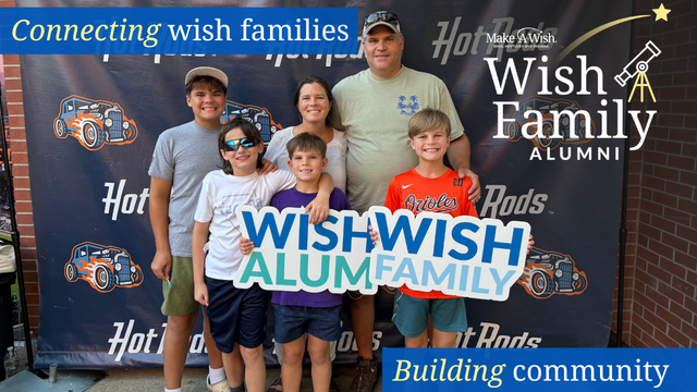 A smiling family of six, including parents and four children, poses in front of a backdrop reading "Wish Family Alumni". The family holds a sign that says "Wish Family Alumni" and are gathered together, smiling. The backdrop features car designs and the Make-A-Wish logo. Text at the top reads "Connecting wish families" and at the bottom "Building community."