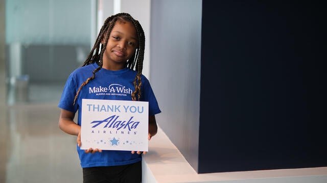 Wish Kid Promise holding Alaska Airlines Sign