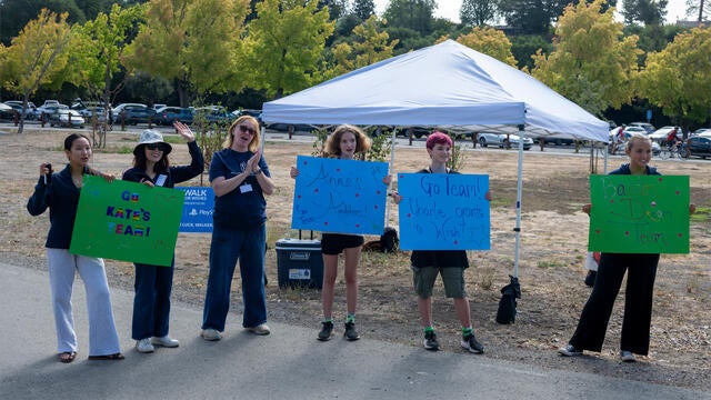 Volunteers holding colorful blue and green signs out on the course