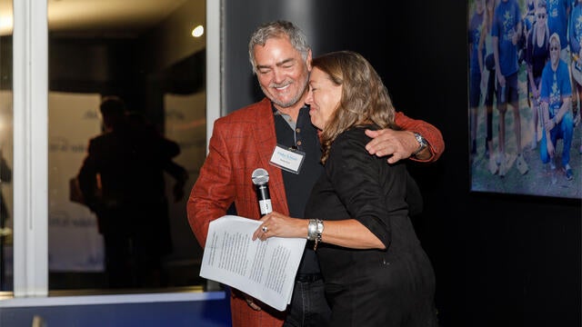 Make-A-Wish Greater Bay Area CEO Betsy Biern hugging Champion of Hope award winner Andy Paul on stage